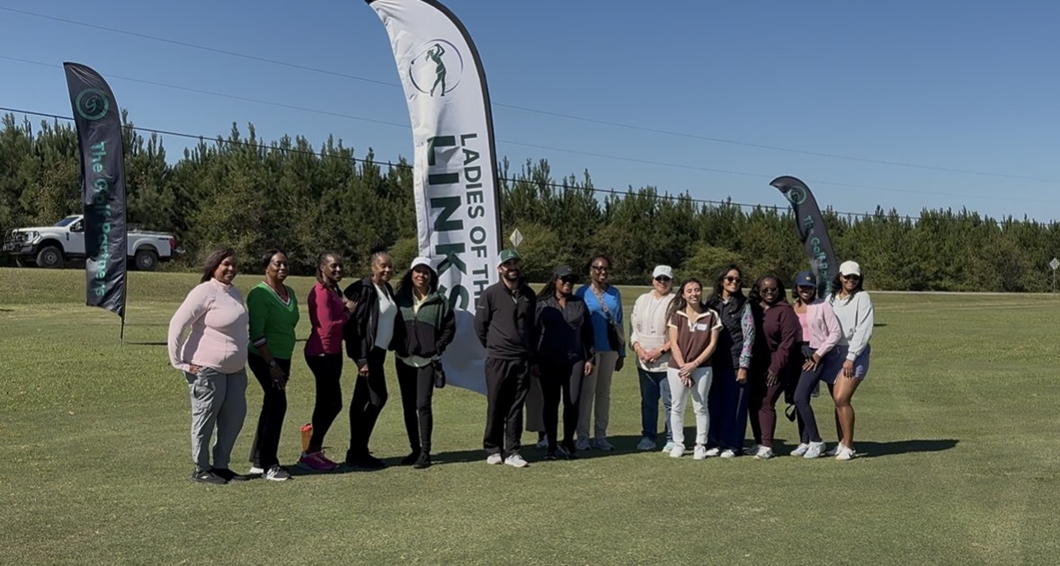 A group of about fifteen women smiling together on the range at Applewood in front of a Ladies of the Links banner, at the first Ladies of the Links event.